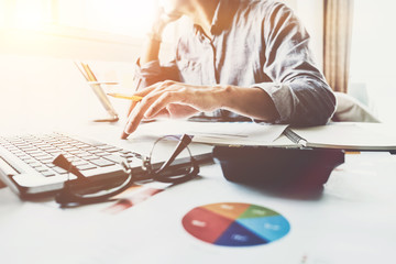 Young accountant hand holding smartphone to call marketing consultants and using laptop computer to analyze sales growth in the global workplace market. accounting concept