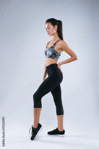 Beautiful and sexy sport woman posing as sportwoman in studio over gray backgrou Poster Mural XXL