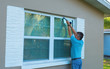 © Michael O'Keene - Homeowner caulking window with a caulk gun, an important part of weatherproofing homes and houses against rain, wind, hurricanes and storms.