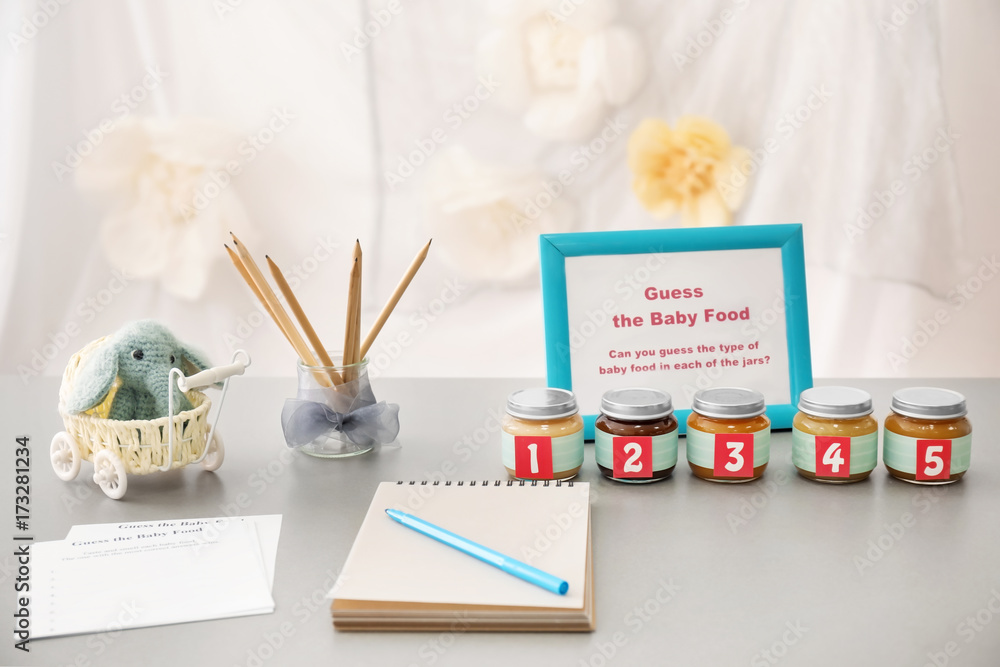 Notebook and jars with different puree on table. Game "Guess taste" for baby shower party