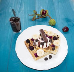 A photo of two Viennese wafers, poured with chocolate with berries and ice cream on a wooden table on the boards. chestnuts, tea, jam, autumn