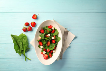 Wall Mural - Plate with strawberry spinach salad on wooden table