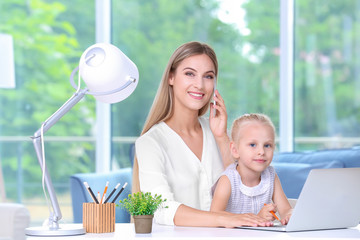 Wall Mural - Busy young woman with her daughter at home