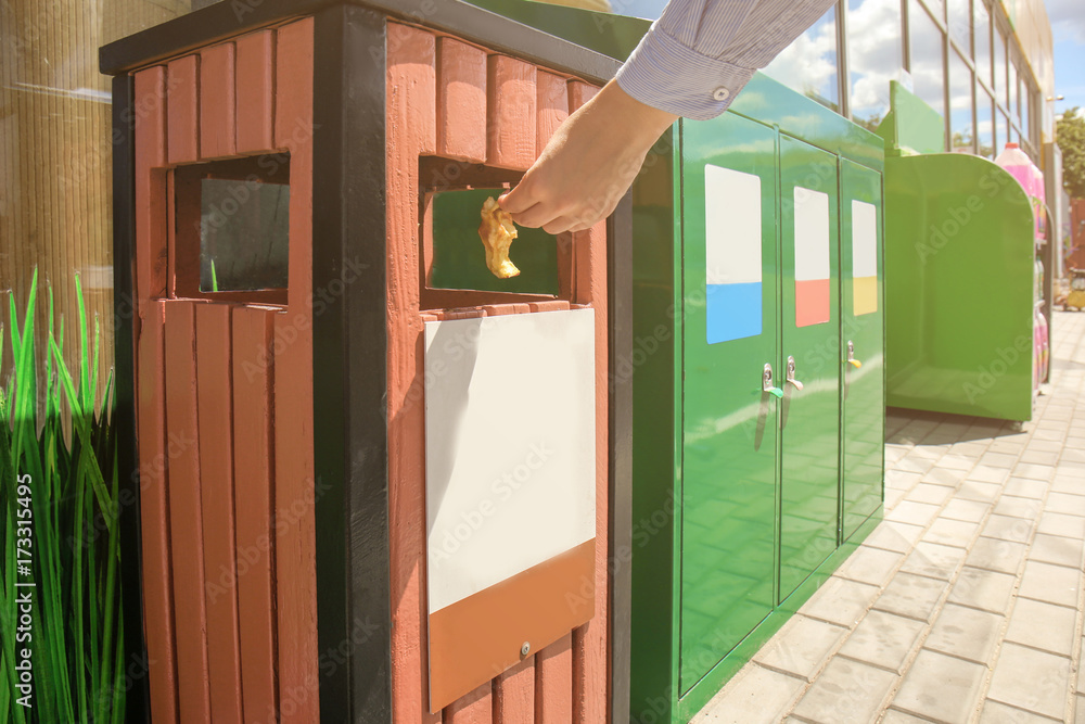 Woman throwing apple stump into litter bin outdoors