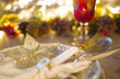 Christmas table setting, layout with cutlery, star and pine cones decoration and a vintage red crystal goblet, with celebration lights shining on the blurry background for a bokeh effect.
