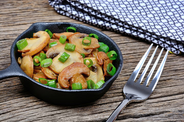 Canvas Print - Champignon with green onion in a pan on table