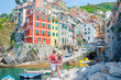 © travnikovstudio - Young family with great view at old village Riomaggiore, Cinque Terre, Liguria, Italy. European italian vacation.
