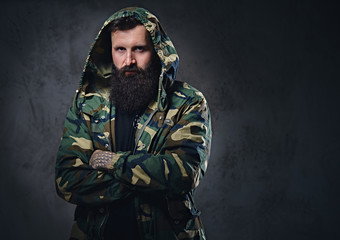 Canvas Print - Urban look bearded male with crossed arms dressed in a camouflage jacket.