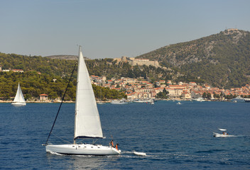 Wall Mural - Yacht in Hvar harbour with Hvar old town at the background, Croatia