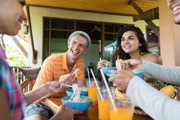 Wall Mural - group of young people talking while eating noodles soup traditional asian food friends dining togeth
