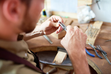 Wall Mural - Closeup of jeweler making rings in workshop setting precious stone on it at work station with different tools