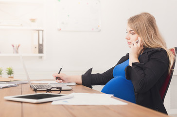 Pregnant business lady at work talking on phone