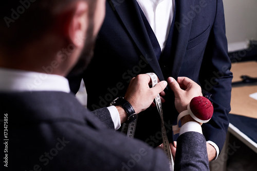 Cuadros en Lienzo Over shoulder view of bearded fashion designer fitting bespoke suit to model, cl