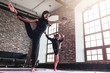 © undrey - Smiling mother and cute little daughter in black sportswear doing standing split leg stretching exercise keeping balance