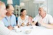 © pressmaster - Group of friendly senior people gathered in cafe for talk by cup of coffee
