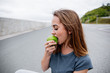 © pantovich - portrait of young charming woman biting green Apple background summer Park