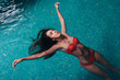Portrait of slim young woman relaxing in swimming pool floating on back