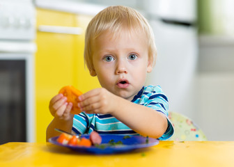 Wall Mural - Little boy eating healthy food at home or nursery