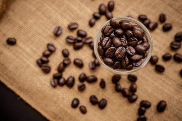 Wall Mural - Coffee bean grain in a glass bottle on black table with sack fabric