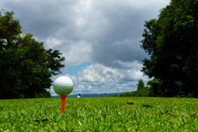 Close Up Of White Golf Ball On Orange Tee At Tee Off With Golf Course Background And Blue Sky And Cloud At Mae Moh Golf Course Hole 1, Down Hill Layout, Lampang, Thailand. Copy Space For Your Text.