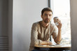 © Cookie Studio - Young unshaven handsome caucasian guy in casual clothes sitting in cafeteria, drinking coffee, resting after hard day on work.