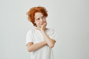 Wall Mural - Close up portrait of little ginger boy with freckles thoughtfully looking aside remembering if he turns off iron before school.