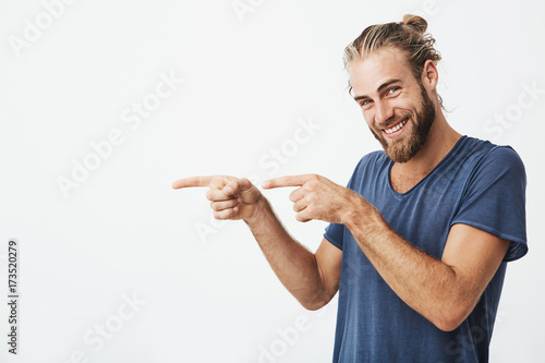 Fotografía Joyful mature guy with beard posing for article in university newspaper pointing aside with fingers on both hands and smiling