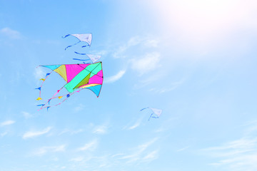 Wall Mural - Colorful kite flying in the blue sky through the clouds