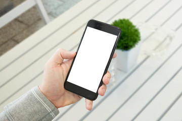 Wall Mural - mobile phone showcase. black smart phone mockup. white wooden desk with plant in background.