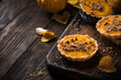 Pumpkin mini pie, tartlet made for Thanksgiving day on old wooden background. Healthy autumn food concept with copy space. Dark photo.