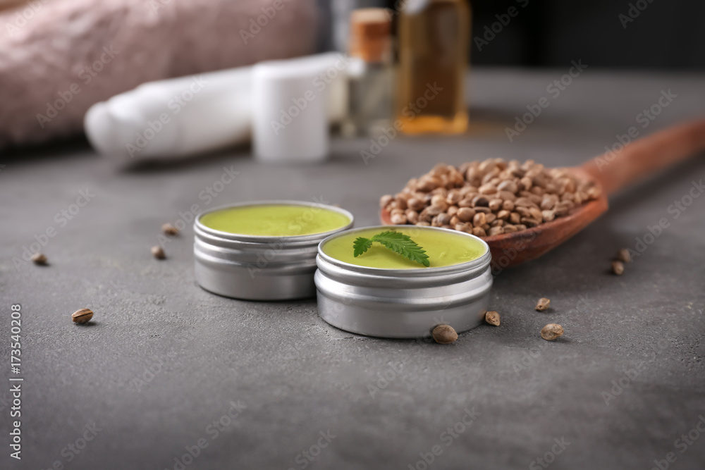 Jars with hemp lotion on grey background