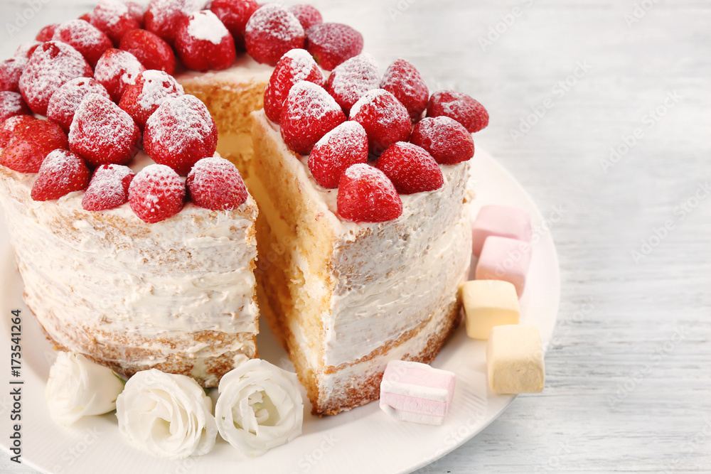 Delicious cake decorated with strawberries on white plate
