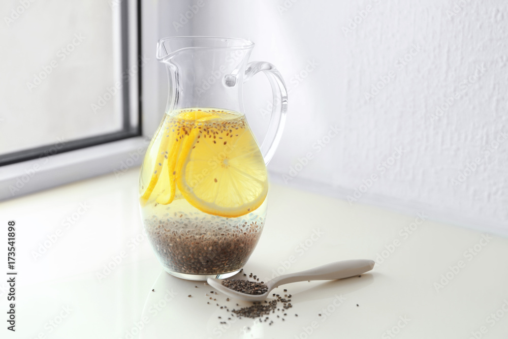 Glass pitcher with water, chia seeds and lemon slices on windowsill