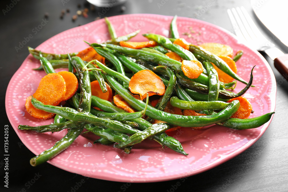 Pink plate with delicious green beans and carrot slices on table