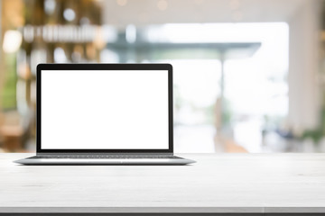 Wood table top with blank screen laptop on blurred abstract background interior view inside reception hotel or modern hallway for background