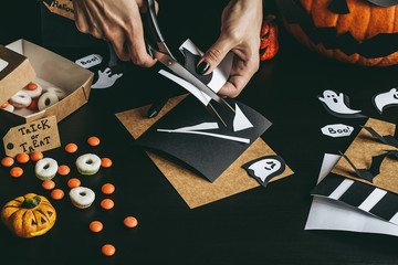 Wall Mural - Halloween preparation. Hands making halloween decoration using craft paper