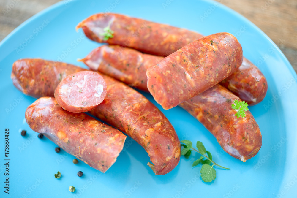 Foto de Stock Rohe Wurst auf blauem Teller | Adobe Stock