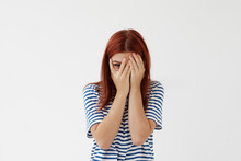 Picture Of Shy Timid Teenage Girl With Colored Hair Covering Face With Hands And Peeping Through Her Fingers At Camera. Young Woman Hiding Her Face Being Frightened, Scared Or Ashamed. Body Language