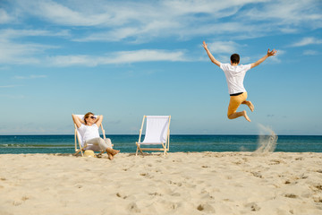 Wall Mural - Woman and man relaxing on beach