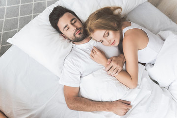 Happy man and woman sleeping in bed