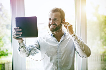 smiling businessman with digital tablet and earphones calling with video conference