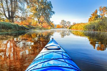 view from the blue kayak on the river banks with autumnal yellow leaves trees in fall season. the se