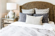 Closeup of new bed comforter with decorative pillows, headboard in bedroom in staging model home, house or apartment