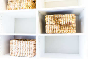 Poster - Closeup of woven straw baskets in modern minimalist white closet or laundry room with bright light in staging model house or apartment