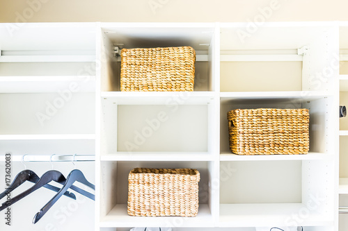 Fotografie, Obraz Closeup of woven straw baskets in modern minimalist white closet or laundry room