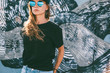 © Alena Ozerova - Model wearing plain tshirt and sunglasses posing over street wall