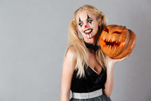 Smiling Blonde Woman In Halloween Make-up Posing With Carved Pumpkin