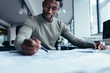 © Jacob Lund - Young man working on blueprint at desk in office