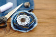 Denim flower accessory. Scissors, thread, thimble, needle, female old jeans on a wooden table. Recycled denim craft idea. Easy and cheap crafts for kids. Closeup