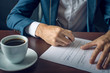 © Artem - Businessman signs important legal documents on the desktop with Cup of coffee